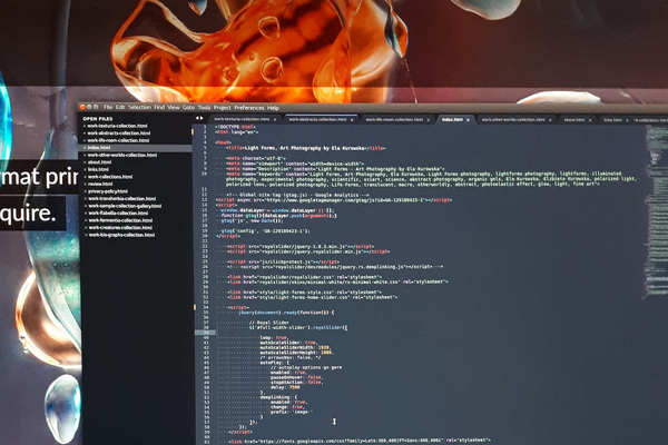 Working on web design for lightforms.ca code and website - A photo of the computer display featuring one of the lightforms.ca homepage slideshows and code text editor.
